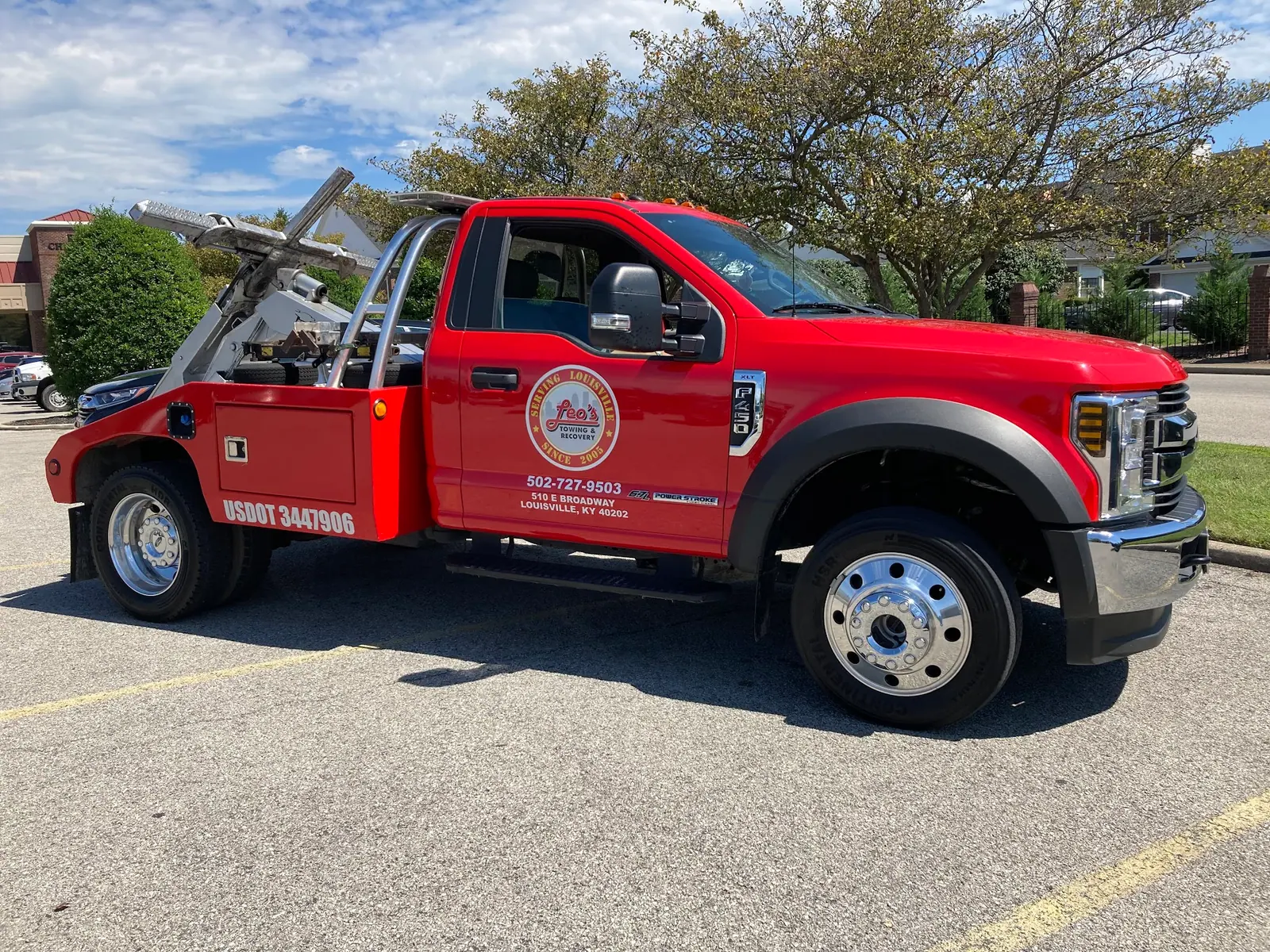 Leo's red wrecker truck parked in a Louisville lot, side view