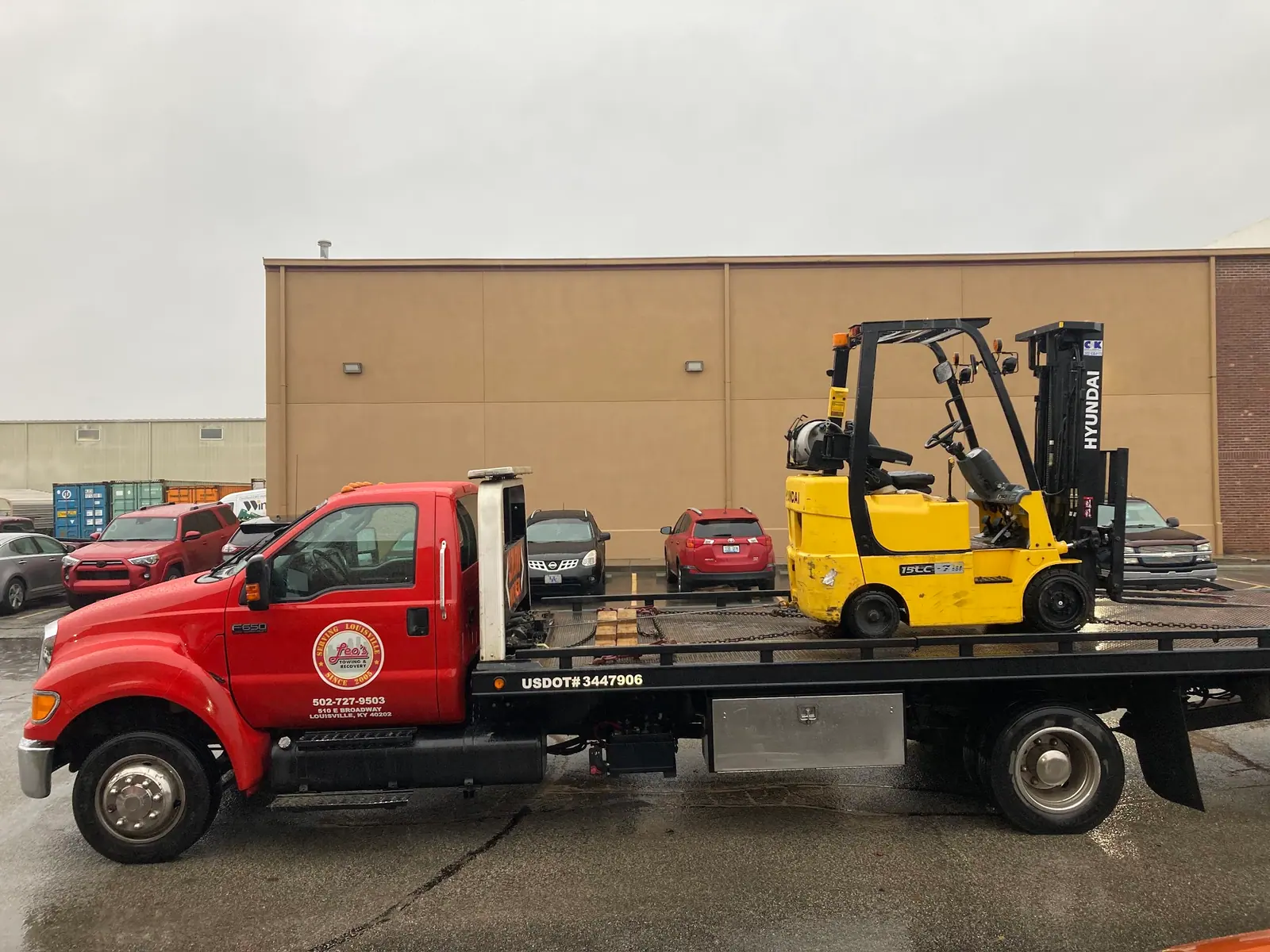 Leo's red flatbed carrying a yellow forklift